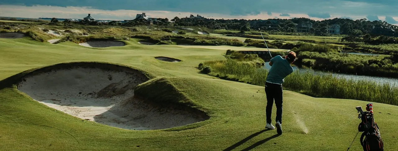 A golfer on a links course under a dramatic sky