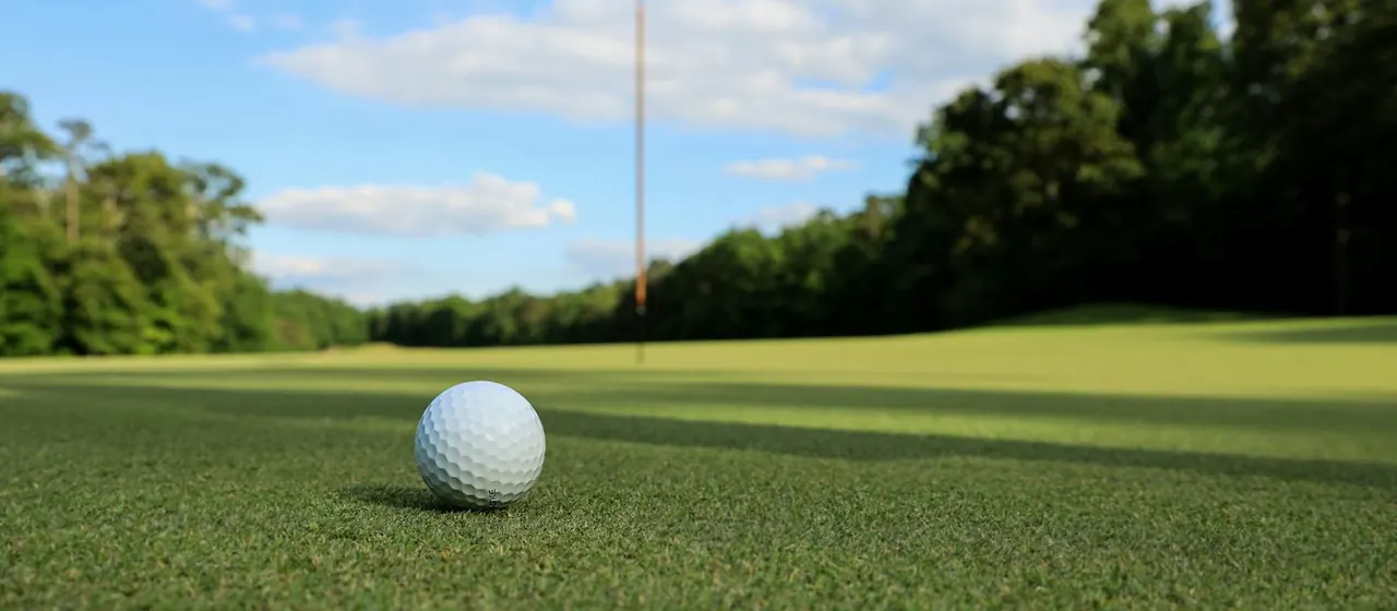 A golf ball on the green with the flag behind